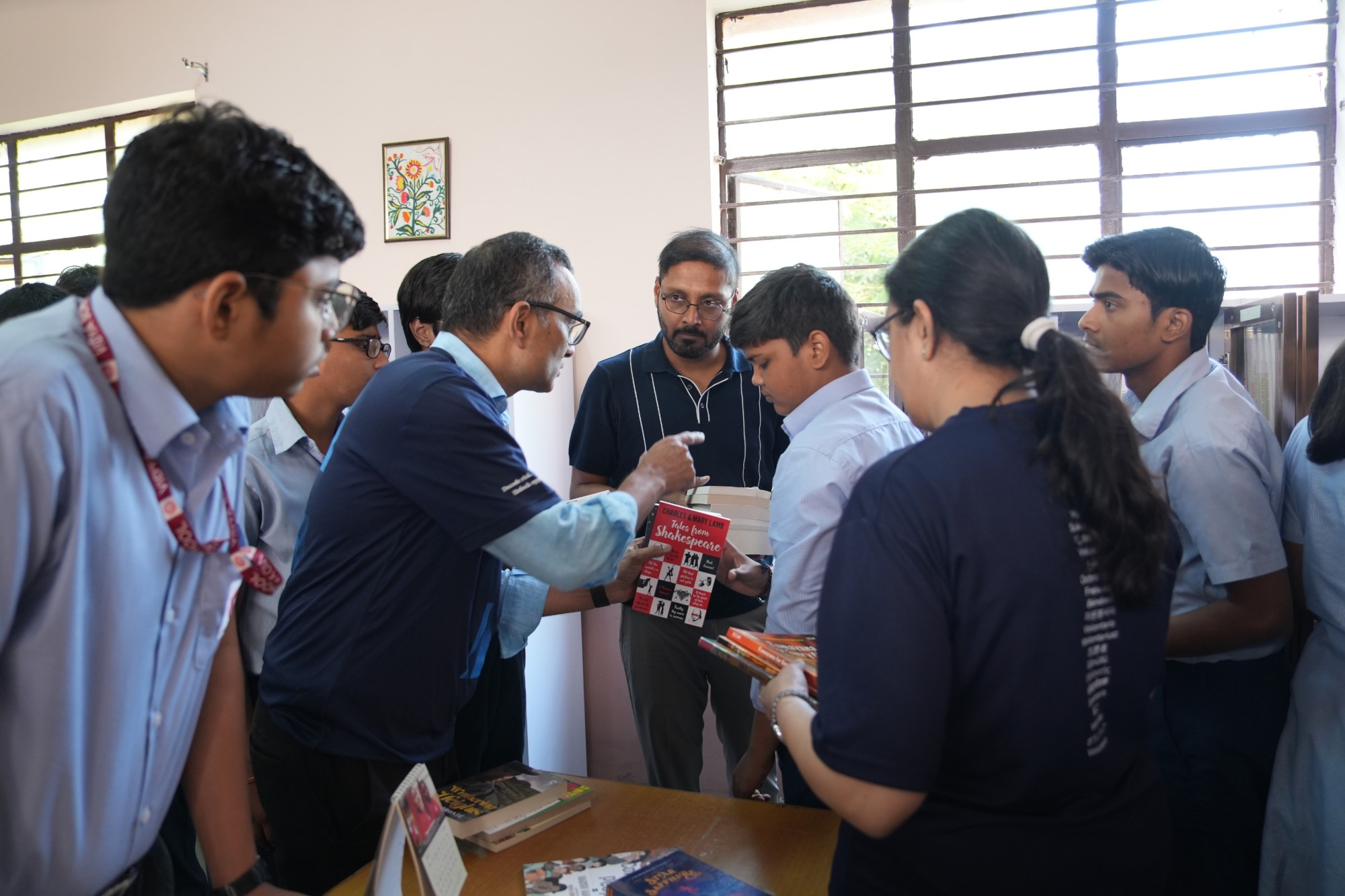 An ICRA volunteer handing out books to students in a school library