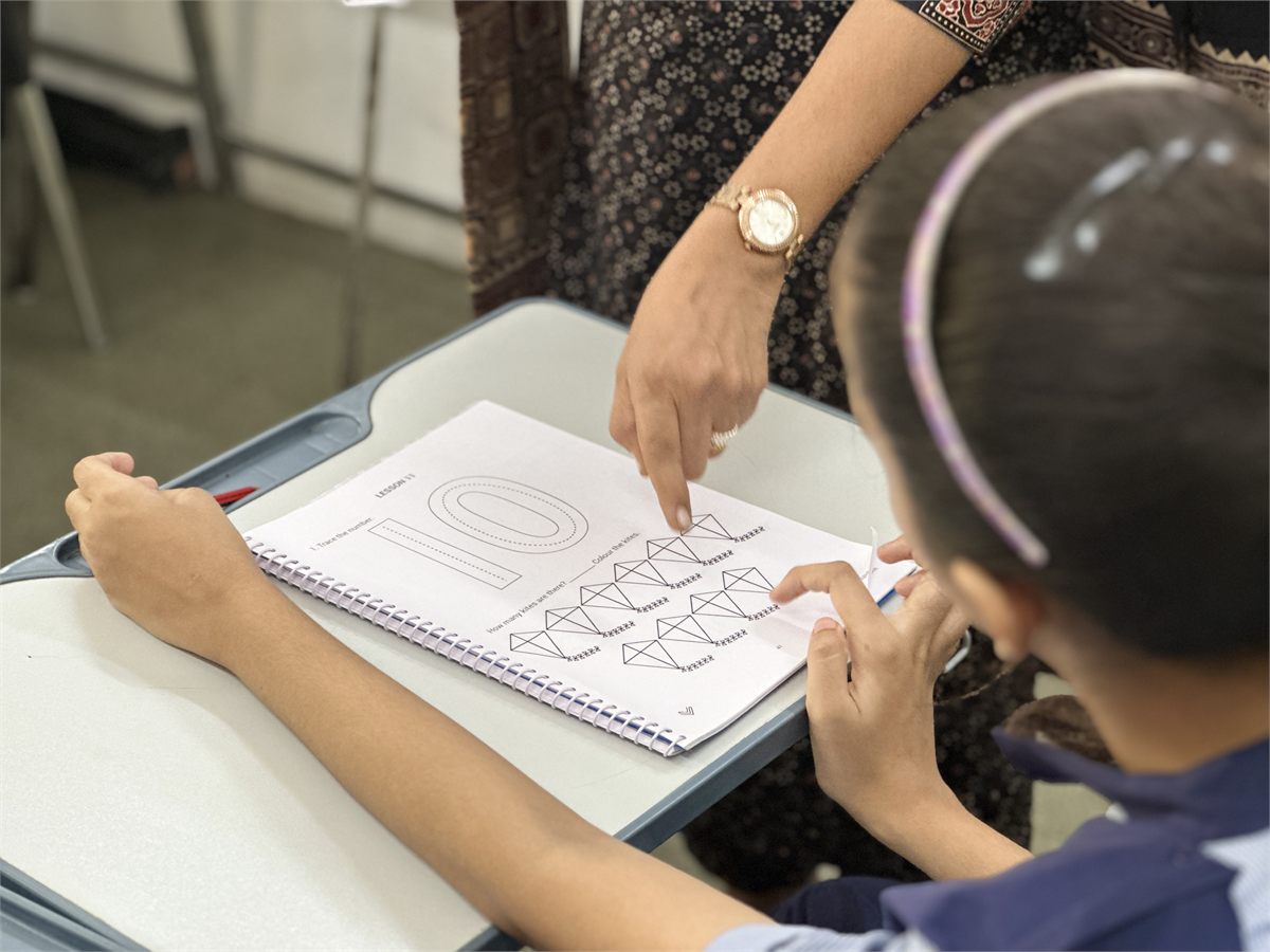 A teacher guiding a student through a worksheet at a special school